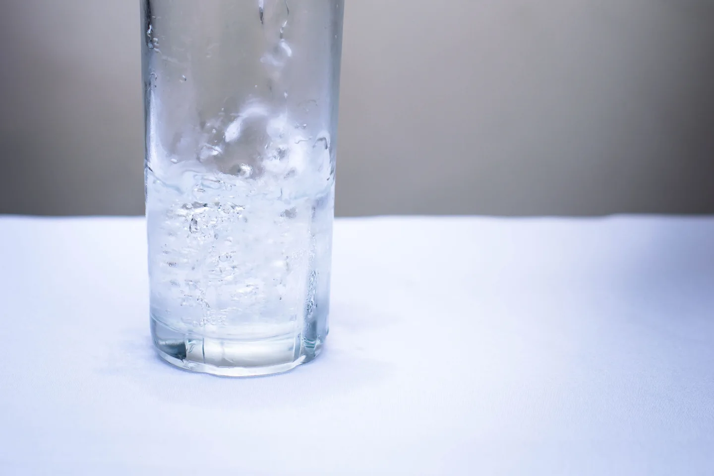 Струя воды наполняет прозрачный стакан