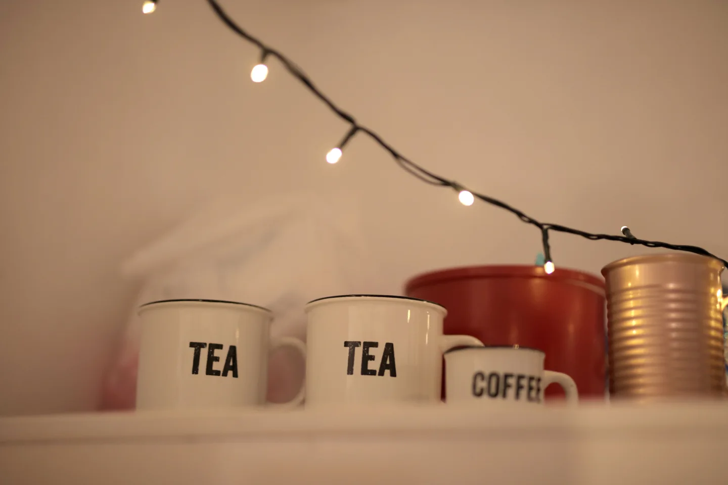 Кружки с надписями Tea и Coffee на полке под гирляндой